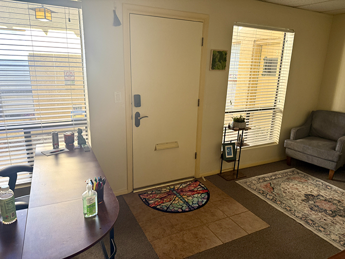 The entrance to HazMatt Holistic Healing in Flagstaff features large windows that fill the lobby with natural light, a colorful dragonfly welcome mat, comfortable seating, and a calm, peaceful atmosphere for massage clients.