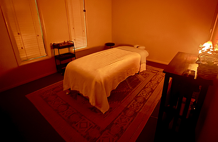 A warmly lit massage treatment room at HazMatt Holistic Healing in Flagstaff, Arizona, featuring a massage table with fresh white linens, a Himalayan salt lamp, and calming ambient lighting designed for relaxation and therapeutic massage.